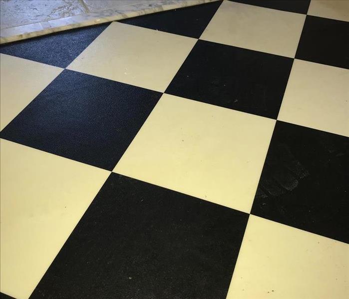 Black and white checkered floor with dirty and white marks on black portion of tiles.
