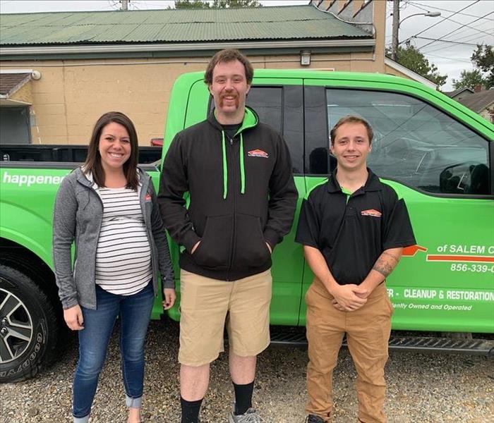 three team members in front of bright green truck